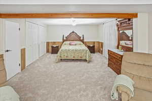 Bedroom featuring light colored carpet and wooden walls