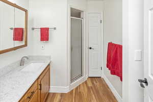 Bathroom featuring vanity, hardwood / wood-style flooring, and a shower with door