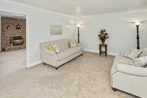 Carpeted living room with a fireplace and crown molding