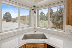 Interior details with light stone countertops, sink, and hanging light fixtures