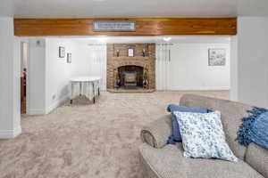 Carpeted living room with beam ceiling and a wood stove