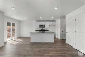 Kitchen with dark hardwood / wood-style flooring, white cabinetry, a center island with sink, and sink