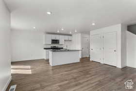 Kitchen with white cabinets, a center island with sink, and dark hardwood / wood-style floors