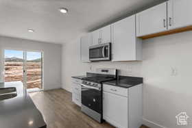 Kitchen with white cabinetry, dark wood-type flooring, and appliances with stainless steel finishes