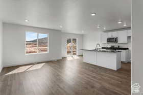 Kitchen featuring white cabinets, sink, a center island with sink, and dark wood-type flooring