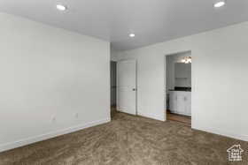 Unfurnished bedroom with dark colored carpet and ensuite bath