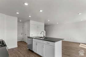 Kitchen featuring sink, dark hardwood / wood-style floors, a center island with sink, white cabinets, and appliances with stainless steel finishes