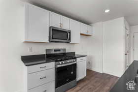 Kitchen featuring white cabinets, appliances with stainless steel finishes, and dark wood-type flooring