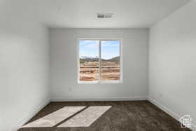 Empty room featuring dark colored carpet