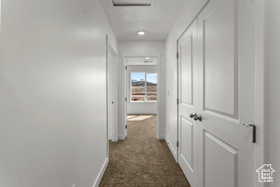 Hall featuring dark colored carpet