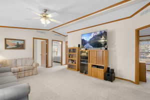 Carpeted living room with ceiling fan and lofted ceiling