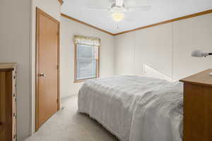 Carpeted bedroom with ceiling fan, ornamental molding, and vaulted ceiling