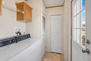 Laundry room with cabinets, independent washer and dryer, and crown molding