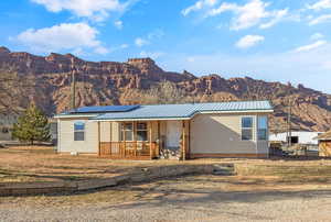 View of front of home featuring a mountain view, a porch, and solar panels