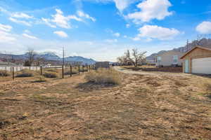 View of yard with a mountain view, an outbuilding, a rural view, and a garage