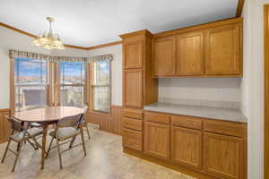 Kitchen with wooden walls, a notable chandelier, decorative light fixtures, and ornamental molding