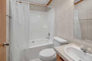 Full bathroom featuring vanity, toilet, shower / bath combo with shower curtain, and ornamental molding