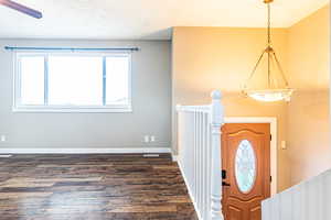 Foyer entrance with a textured ceiling and dark wood-type flooring