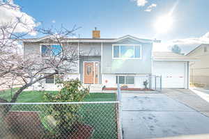 Split foyer home featuring a garage and a front lawn