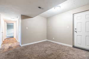 Unfurnished room with a textured ceiling and carpet floors