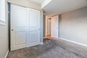 Unfurnished bedroom featuring dark colored carpet and a closet