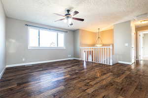 Unfurnished room featuring a textured ceiling, dark hardwood / wood-style floors, and ceiling fan