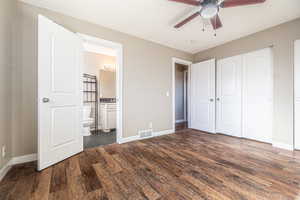 Unfurnished bedroom featuring ceiling fan, a closet, dark wood-type flooring, and ensuite bath