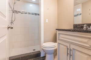 Bathroom with vanity, toilet, and tiled shower