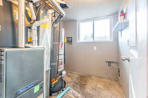 Utility room featuring gas water heater and heating unit, plus laundry hookups