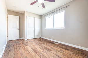 Unfurnished bedroom featuring hardwood / wood-style flooring, ceiling fan, and a closet