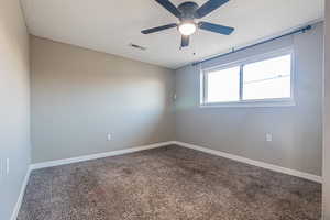 Empty room with ceiling fan and carpet floors