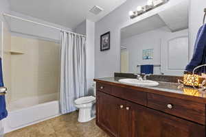 Full bathroom with vanity, shower / tub combo, a textured ceiling, and toilet