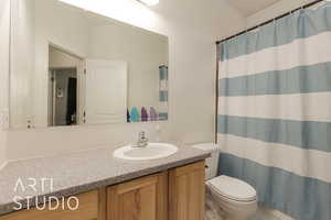 Bathroom featuring a shower with shower curtain, vanity, and toilet