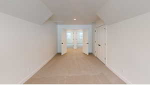 Hallway with baseboards, a textured ceiling, and light colored carpet