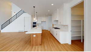 Kitchen featuring a kitchen island with sink, visible vents, white cabinetry, light countertops, and appliances with stainless steel finishes