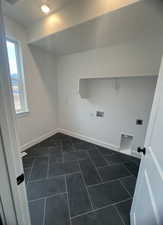 Washroom with electric dryer hookup, washer hookup, and dark tile patterned flooring