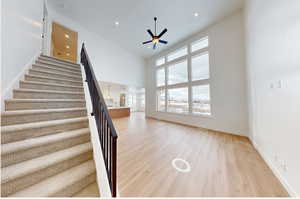 Stairs with ceiling fan, recessed lighting, a high ceiling, wood finished floors, and baseboards