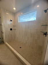 Bathroom with tiled shower and tile patterned floors