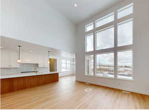 Kitchen with light wood finished floors, light countertops, hanging light fixtures, decorative backsplash, and white cabinetry