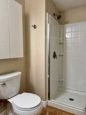 Bathroom featuring toilet, a shower, and wood-type flooring