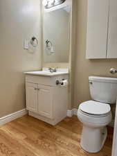 Bathroom with hardwood / wood-style floors, vanity, and toilet