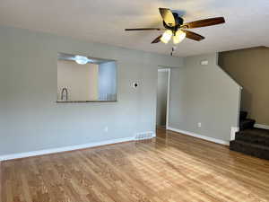 Unfurnished living room with ceiling fan, light hardwood / wood-style floors, and a textured ceiling