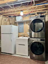 Washroom featuring electric panel, stacked washer and clothes dryer, and sink