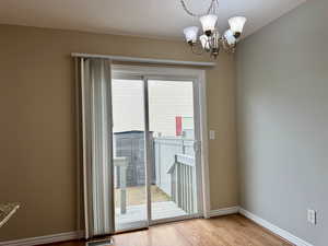 Doorway to outside featuring a notable chandelier, light wood-type flooring, and plenty of natural light