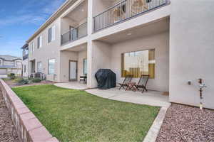 Rear view of property with a lawn, a patio area, a balcony, and central AC