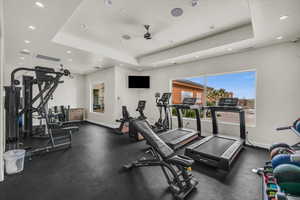 Workout area with ceiling fan and a raised ceiling