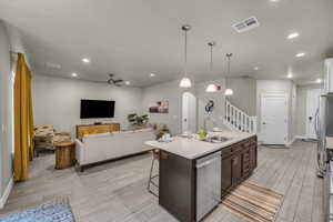 Kitchen featuring dishwasher, a kitchen island with sink, sink, ceiling fan, and dark brown cabinets