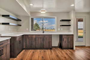 Kitchen featuring open shelves, dark brown cabinets, a textured ceiling, light wood-type flooring, and recessed lighting