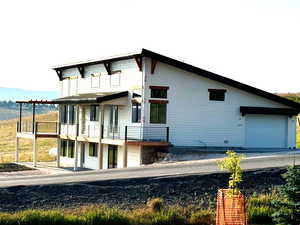 Back of property featuring a garage and a balcony