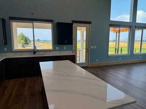 Kitchen with light stone counters, sink, and dark wood-type flooring